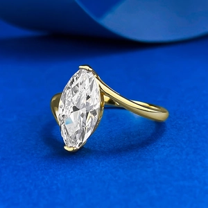Macro detail of marquise-cut crystal ring with golden asymmetrical streamlined band