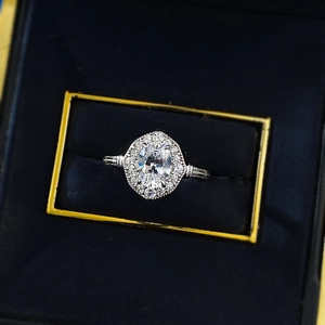 Makroaufnahme des ovalen Kristallrings mit Halo-Fassung in einer blauen Box