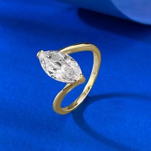 Marquise cut sparkling diamond ring with S-curved gold band on blue textured background