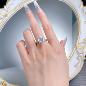 Detail of cushion cut halo ring with pave diamonds on model hand with elegant mirror background