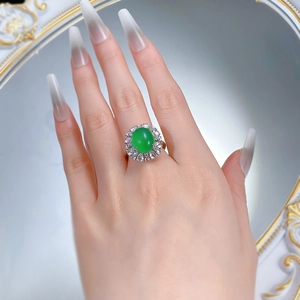 Close-up of a silver ring with a large oval green chalcedony stone and diamond halo