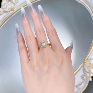 Détail d'une bague ovale avec halo et anneau doré portée à la main devant un miroir