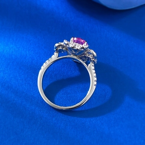 Gros plan d'une bague ovale avec pierre rose et halo de diamants sur fond bleu