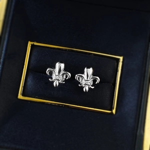 Macro detail of S925 silver Fleur-de-lis stud earrings with zircon in a navy velvet box