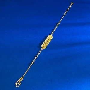 Detailed shot of golden five-coin bracelet with intricate chain and S-hook clasp