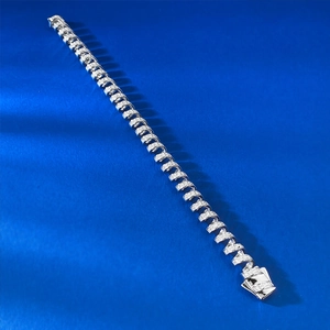 Gros plan détaillé d'un bracelet spirale argenté serti de zircons sur fond bleu vif