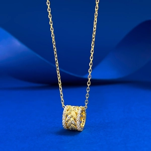 Detailed view of a gold wheat-engraved cylinder pendant with zircon stones on silk