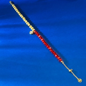 Détail des perles rouges facettées et du bracelet en argent S925 doré avec pendentif