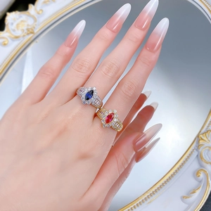 Macro shot of silver and gold marquise cut rings with blue and red stones on retro mirror