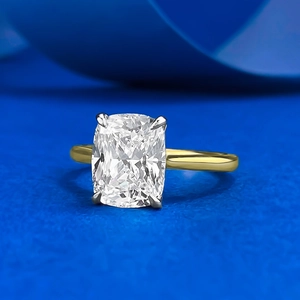 Close-up of cushion cut cubic zirconia ring with gold band on blue silk background