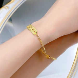 Close-up of gold coin bracelet on wrist featuring paperclip chain and adjustable clasp