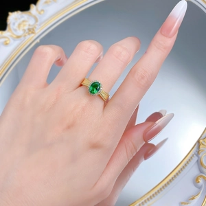 Macro detail of vintage gold ring with emerald green stone and sparkling halo