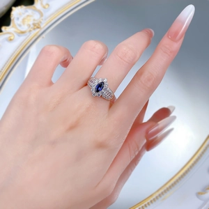 Close-up of a marquise-cut royal blue gemstone ring with diamond accents on a model hand