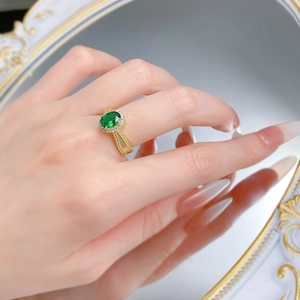 Macro shot of gold textured ring with oval green emerald stone and halo diamond setting