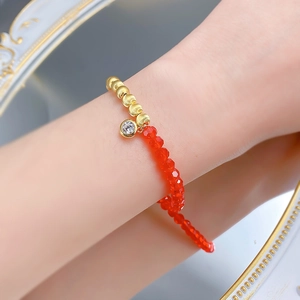 Gros plan d'un bracelet perlé doré S925 avec pierres œil-de-chat rouges et pendentif zircon
