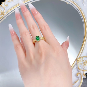 Detail of vintage gold ring with oval emerald gemstone and surrounding zircon stones