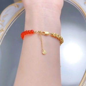 Détail du bracelet en argent S925 doré avec perles rouges au poignet devant un miroir