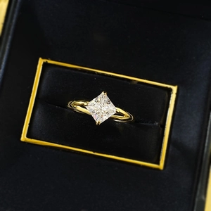 Macro view of princess-cut white diamond ring set in gold, displayed in a black velvet box