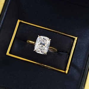 Macro view of cushion-cut diamond ring in golden finish inside a velvet box
