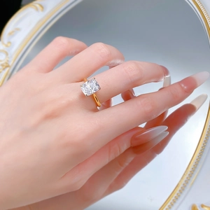 Close-up of a cushion-cut solitaire diamond ring in gold setting worn on a hand