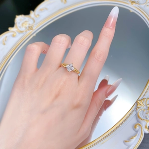 Detail of princess cut white stone gold ring shown on hand with mirror reflection