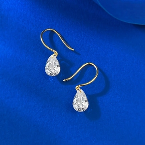 Elegant gold drop earrings with pear-cut crystals on a deep blue background