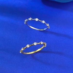 Macro shot of silver and gold S925 stackable rings with round zircon stones on blue texture