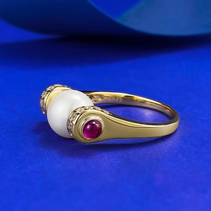 Macro view of S925 silver gold-plated ring with white pearl and red gemstone detail
