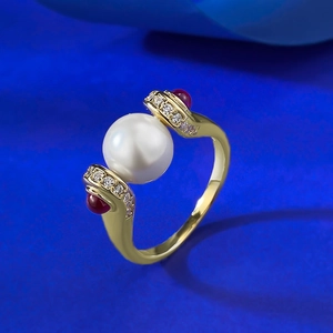 Detail of vintage gold ring with large white pearl, red gems and pavé crystals