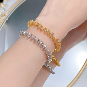 Macro detail of gold and silver spiral bracelets featuring pave-set sparkling crystals