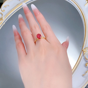 Close-up of S925 sterling silver gold-plated ring with oval red gemstone on a hand