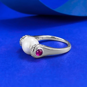 Detailed side view of silver ring featuring a large white pearl and red gemstones