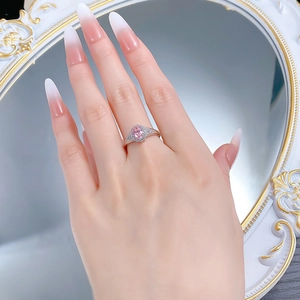 Close-up of pink oval gemstone ring with cluster diamonds worn by a model against a mirror