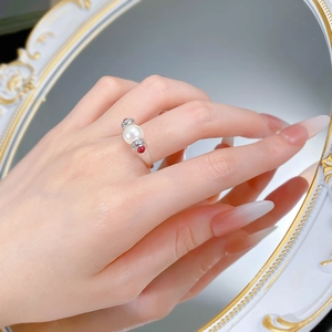 Macro detail of S925 silver ring featuring a large pearl and red side gems on hand