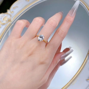 Close-up of a gold 8x10mm oval solitaire ring on a finger with a mirror background