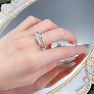 Detail showing five emerald-cut white stones set in silver band worn on a finger