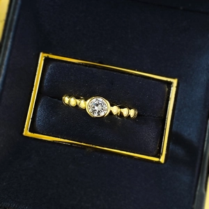 Dettaglio macro dell'anello a sfere dorato con zircone a taglio rotondo incastonato a castone