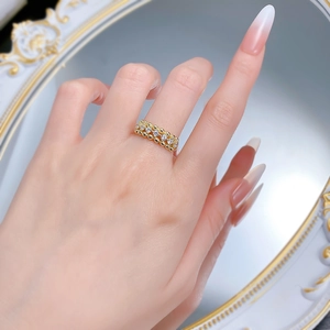 Detail of gold-plated S925 silver hollow mesh ring with sparkling white stones on finger