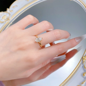 Reflet artistique d'une bague avec diamant blanc taille poire sur le doigt