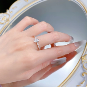 On-hand view of silver ring with oval clear gemstone and tiny marquise side stones