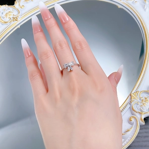 Elegant close-up of a silver bow ring with zircon stones on a model's hand