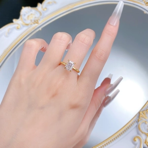 Detail of a 6x8mm rectangle ice cut stone ring on finger with gold plated band