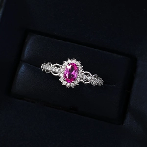 Close-up of pink oval gemstone ring with pavé diamond halo and hollow woven band