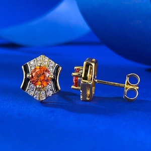 Macro view of hexagonal gold earrings with orange stone and black enamel details