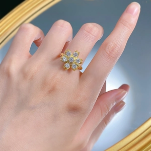 Close-up of a gold daisy flower ring with sparkling zircon petals on a model hand