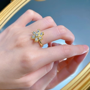 Detail of elegant gold daisy ring with sparkling clear gemstones worn on finger