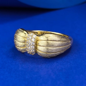Bague nœud élégante en or brossé avec pierres pavées sur fond bleu texturé