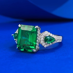 Bague en argent S925 avec pierre verte taille émeraude sur fond bleu foncé texturé