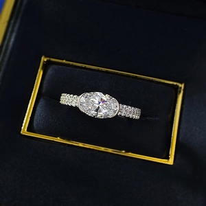 Macro shot of oval-cut gemstone ring with pavé diamond band in a velvet jewelry box