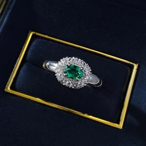 Macro view of oval emerald ring with double diamond halo in luxury velvet jewelry box